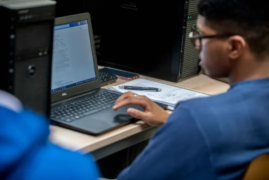 Étudiant travaillant sur un ordinateur portable dans une salle informatique.