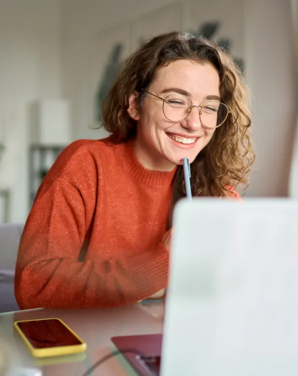 une étudiante souriant derrière un ordinateur 